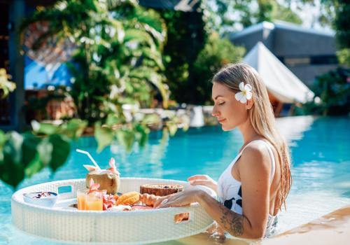 Mujer comiendo frutas en una mesa blanca redonda con un fondo verde